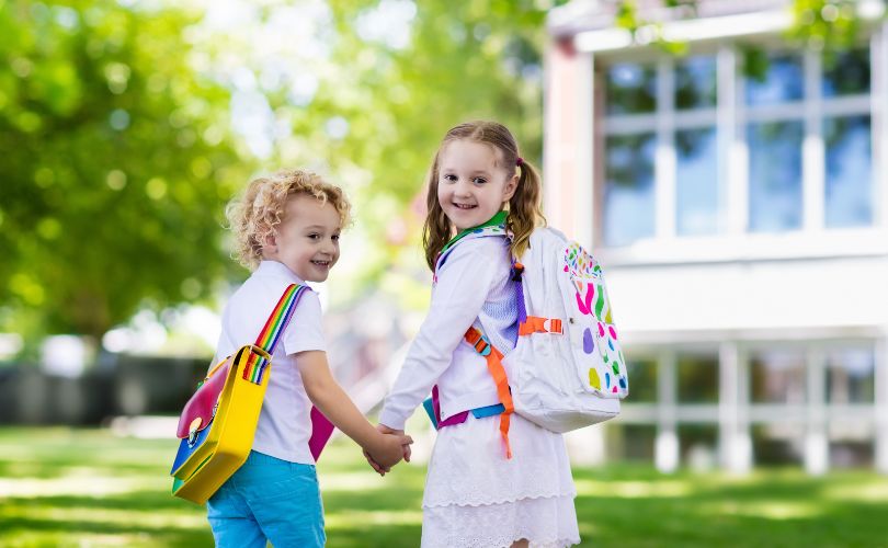 Deux enfants expatriés souriants avec sac à dos, prêts pour leur rentrée scolaire à l’île Maurice